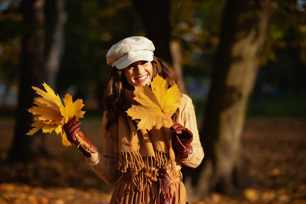 Sonriente mujer moderna con hojas amarillas afuera en el parque de otoño —  Fotos de Stock