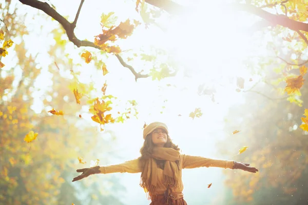 Щаслива жінка насолоджується осіннім і ловлять опадаюче жовте листя — стокове фото