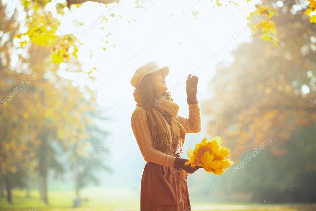 carefree woman with yellow leaves outside in autumn park
