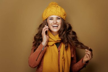 gülümseyen modern kadın akıllı telefon kullanıyor ve bronz arka planda