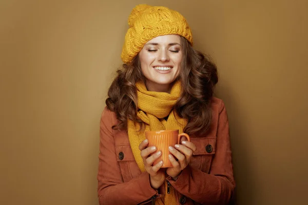 Mujer relajada disfrutando de taza de café con leche de calabaza aislado en beige — Foto de Stock