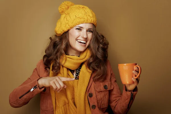Улыбающаяся современная женщина, указывающая на чашку тыквенного латте — стоковое фото