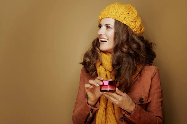 Mulher sorridente com frasco de creme facial olhando para o espaço de cópia — Fotografia de Stock