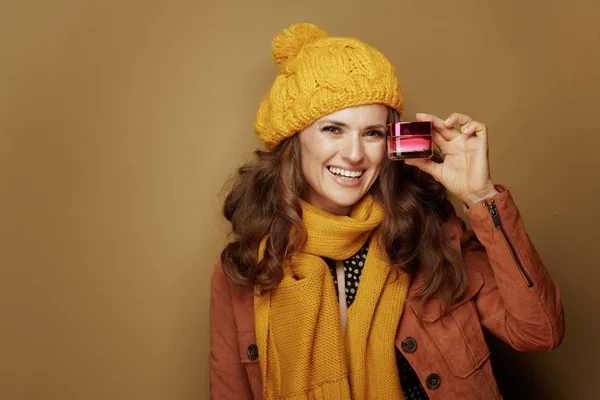 Mujer mostrando tarro de crema facial contra fondo marrón — Foto de Stock