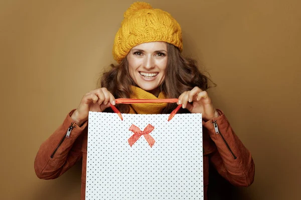 Glimlachende moderne vrouw tonen boodschappentassen op beige achtergrond — Stockfoto