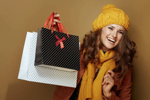 Sorridente donna moderna che mostra borse della spesa su sfondo bronzo — Foto Stock