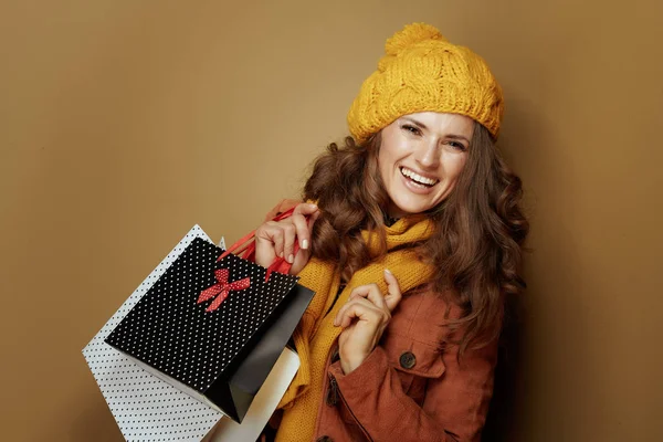 Usmívající se mladá žena s nákupními taškami na hnědém pozadí — Stock fotografie