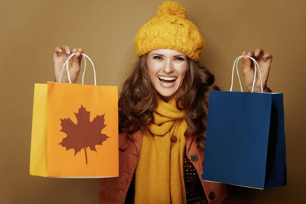 Femme souriante montrant sacs à provisions d'automne isolé sur beige — Photo