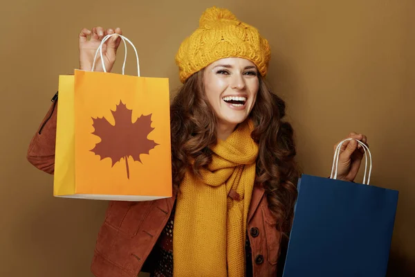 茶色の背景に秋の買い物袋を見せる笑顔の女性 — ストック写真