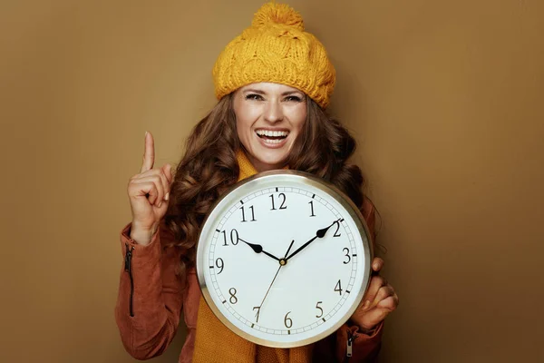 Mulher elegante feliz com relógio redondo apontando para cima no espaço de cópia — Fotografia de Stock