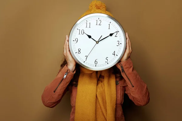 Woman hiding behind round clock remind about autumn time change — Stock Photo, Image