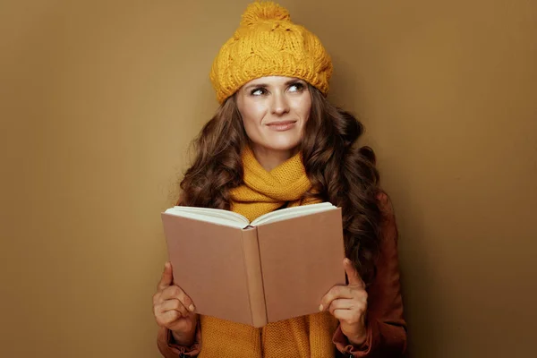 Mujer con libro mirando espacio de copia sobre fondo marrón —  Fotos de Stock