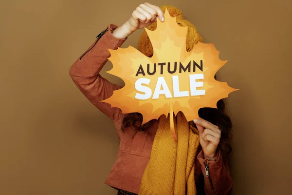 Woman hiding behind autumn sale banner on beige background — Stock Photo, Image