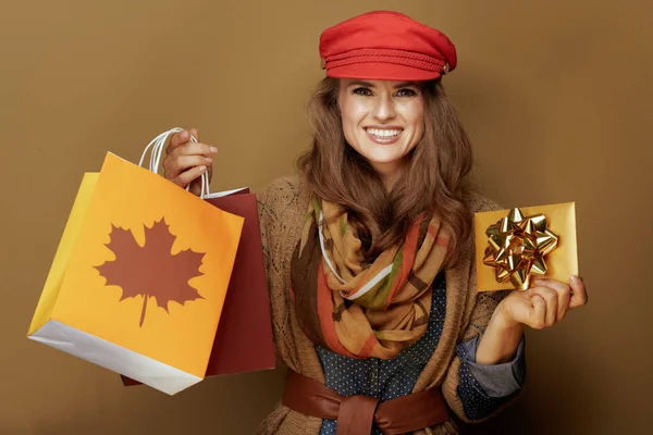 Vrouw van middelbare leeftijd met herfst boodschappentassen en gouden cadeaubon — Stockfoto