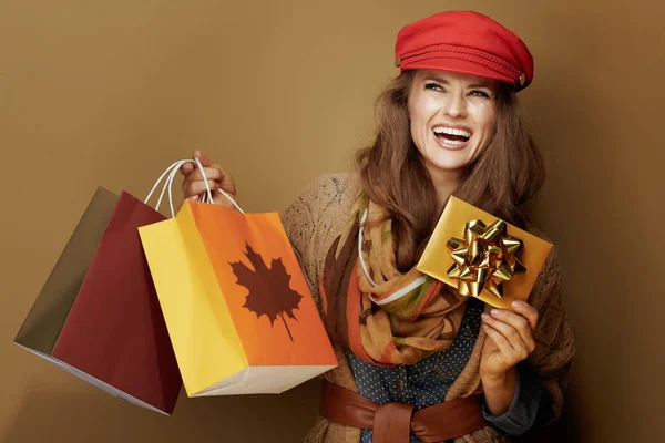 Vrouw van middelbare leeftijd met herfst boodschappentassen en gouden cadeaubon — Stockfoto