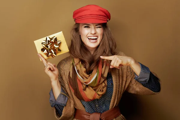Kobieta w średnim wieku wskazując złotą kartę podarunkową na tle brązu — Zdjęcie stockowe