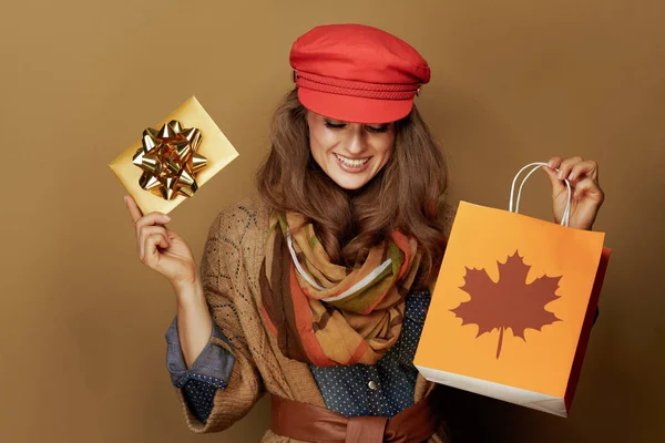 秋の買い物袋と黄金のギフトカードを見せる笑顔の女性 — ストック写真