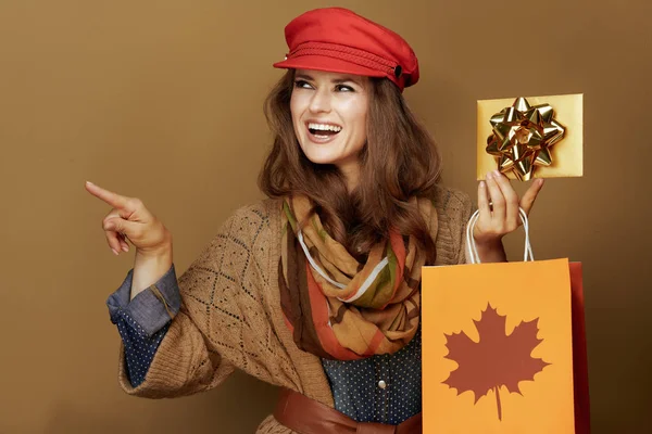 Женщина с сумкой и золотой подарочной картой указывая на что-то — стоковое фото