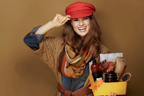 Kobieta pokazując jesień kosmetyki pudełko izolowane na beżowy — Zdjęcie stockowe