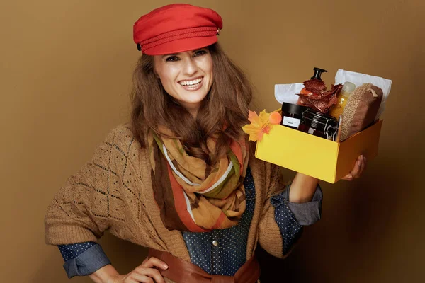 मुस्कुराते हुए फैशनेबल महिला शरद ऋतु सौंदर्य प्रसाधन सामग्री बॉक्स दिखा रही है — स्टॉक फ़ोटो, इमेज