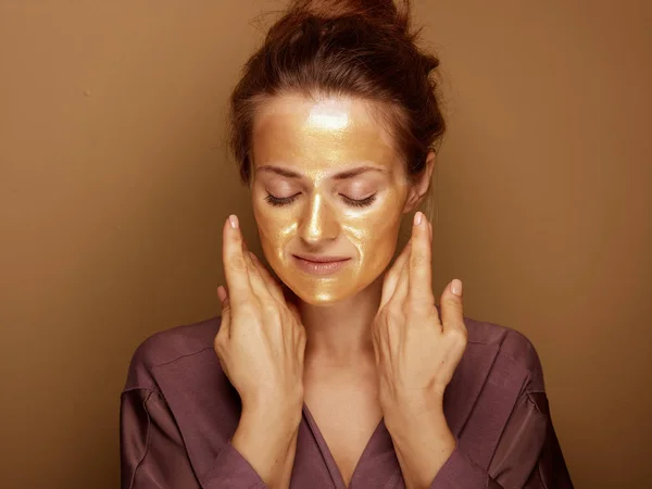 Zrelaksowana kobieta ze złotą maską odizolowana na beżowym tle — Zdjęcie stockowe