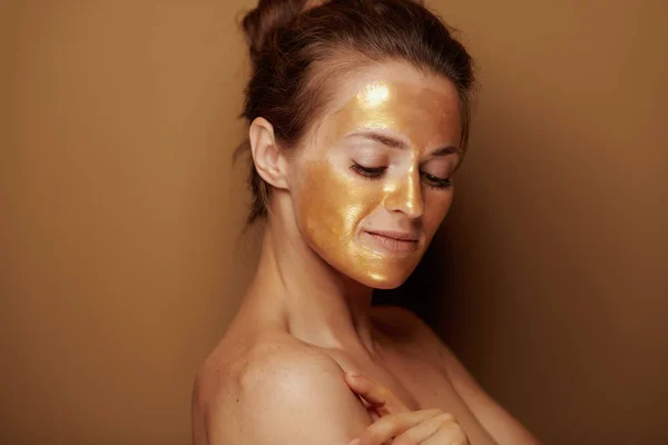 青銅の背景に金色のマスクを持つ現代女性の肖像画 — ストック写真