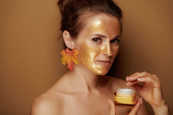 Moderne vrouw met gouden masker met behulp van cosmetische product — Stockfoto
