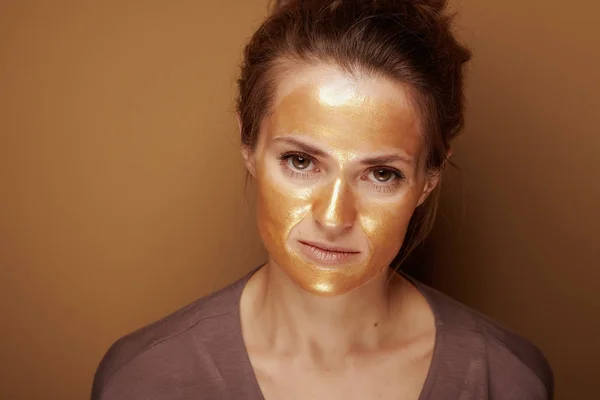 Elegant woman with golden mask isolated on bronze background — Stock Photo, Image