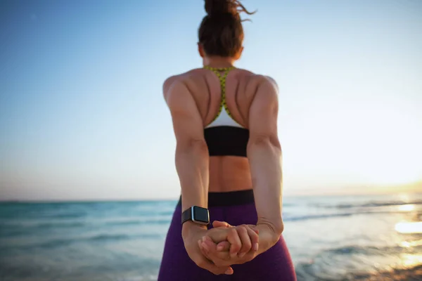 Sett Bakifrån Ung Idrottskvinna Träningskläder Stranden Vid Solnedgången Stretching — Stockfoto