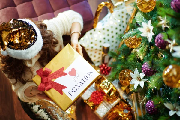 中年时代优雅的家庭主妇 一头乌黑的长发 金色亮片裙 白色毛衣 挂在装饰过的圣诞树下 靠近装有特殊圣诞礼品盒的礼品盒 — 图库照片