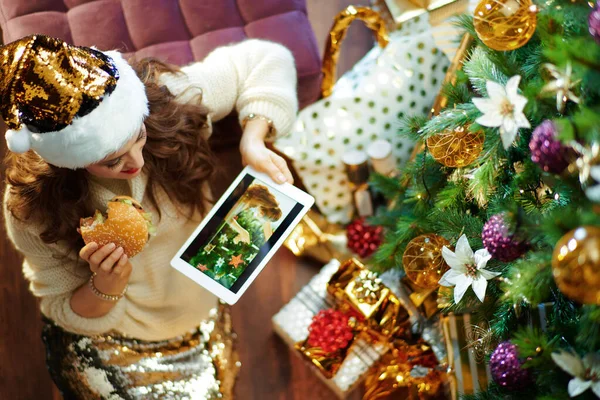 보이는 전통적 전통적 머리에 스커트와 스웨터를 크리스마스 밑에서 햄버거를 태블릿 — 스톡 사진