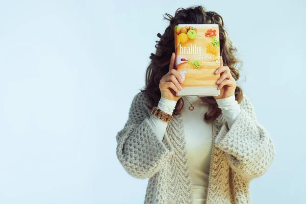 Jovem mulher segurando livro de alimentação saudável na frente da cara — Fotografia de Stock