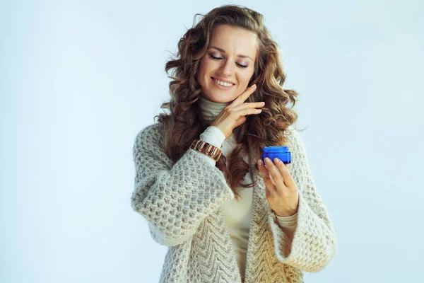 Glimlachende vrouw met winter huidverzorging gezichtscrème aanraken gezicht — Stockfoto