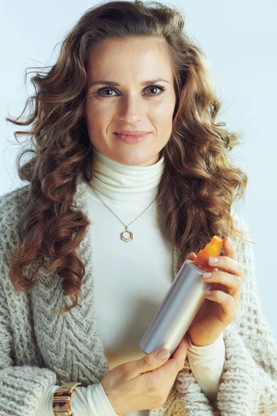 Woman holding hair care product on winter light blue background — ストック写真