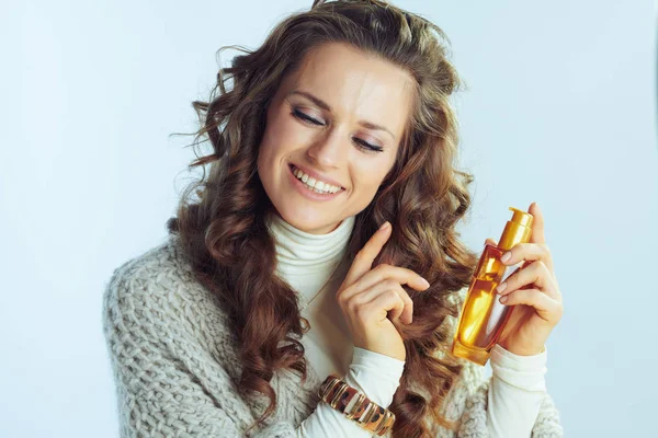 Female with hair care product on winter light blue background — ストック写真