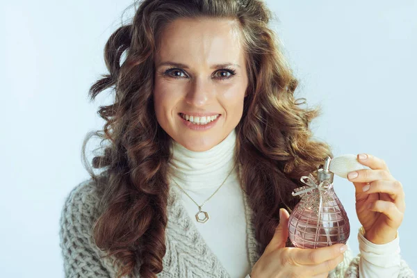 Smiling female applying perfume on winter light blue background — ストック写真