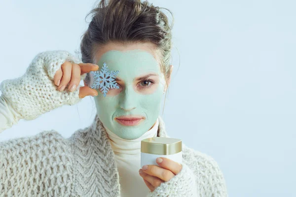 Kozmetik kavanoz ve kar tanesi gösteren yeşil maskeli bir kadın. — Stok fotoğraf