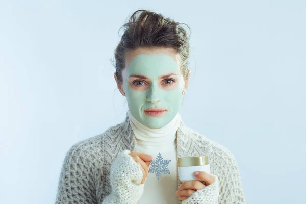 Hemmafru med grön ansiktsmask som håller burk och snöflinga — Stockfoto