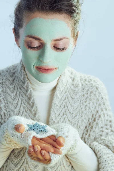 Snygg kvinna med grön ansiktsmask tittar på snöflinga — Stockfoto