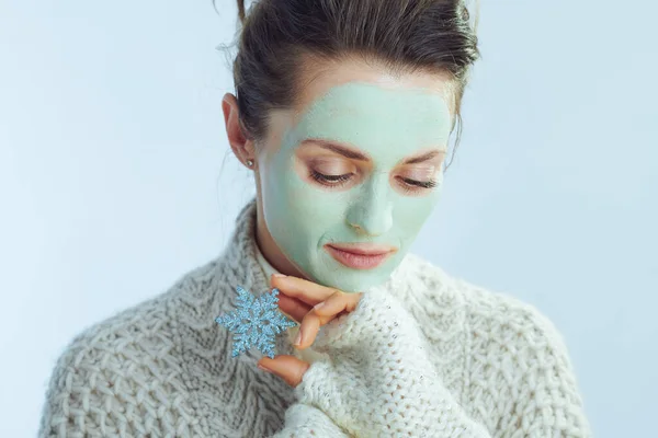 Yeşil maskeli şık bir kadın elinde kar tanesi tutuyor. — Stok fotoğraf