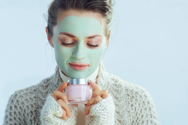 Moderne vrouw met groen gezichtsmasker met cosmetische pot — Stockfoto