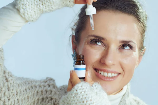 Happy elegant housewife using eye drops as winter eye care — Stock Photo, Image