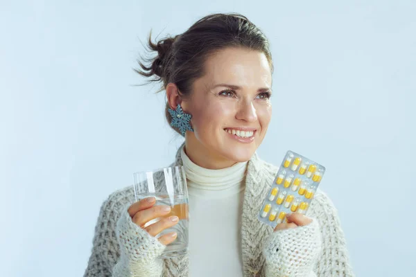 Mulher sorridente com vidro de água e blister pacote de pílulas — Fotografia de Stock