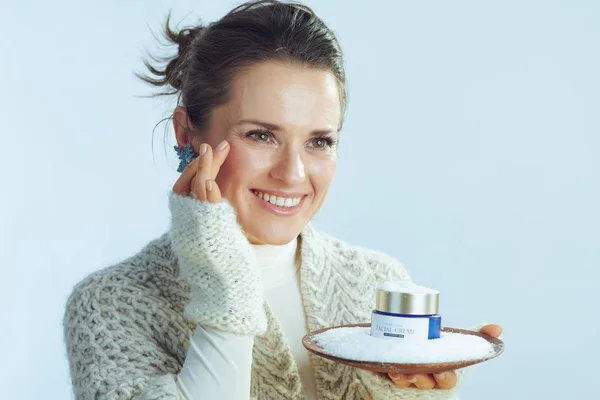 Dona de casa segurando placa com creme entre a neve e rosto tocante — Fotografia de Stock