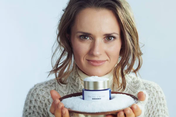 Elegante 40 anos de idade mulher mostrando prato com creme entre a neve — Fotografia de Stock