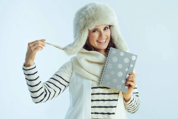 Szczęśliwa kobieta z notatnikiem na tle jasnoniebieskiego zimowego tła — Zdjęcie stockowe
