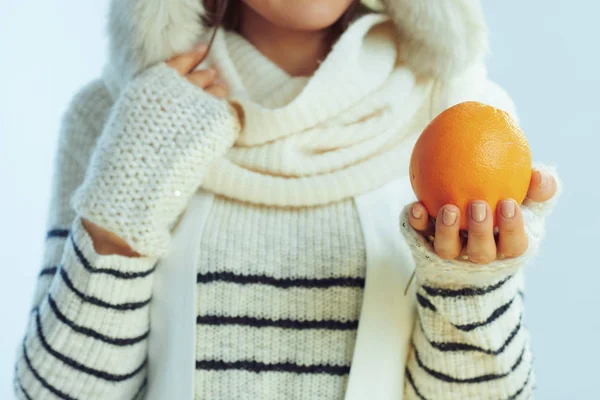 Primer plano de la mujer que muestra naranja en invierno fondo azul claro —  Fotos de Stock