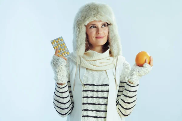 Mujer moderna pensativa con naranja y blister paquete de vitaminas — Foto de Stock