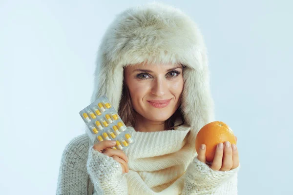 Sonriente joven mujer mostrando naranja y blister paquete de vitaminas — Foto de Stock