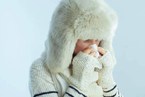 Vrouw vegen neus met servet op winter licht blauwe achtergrond — Stockfoto